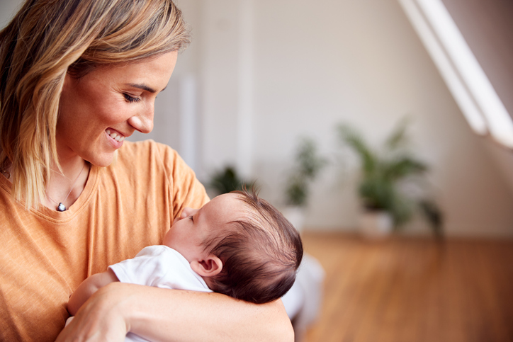 Loving Mother Holding Newborn Baby At Home